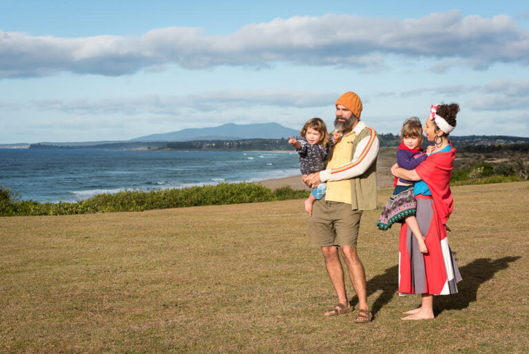A family on grassy verge in front of the ocean.