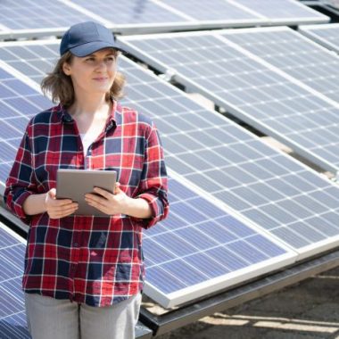 Woman with clipboard standing next to solar array